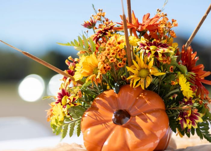 glass pumpkin in front of orange bouquet of flowers