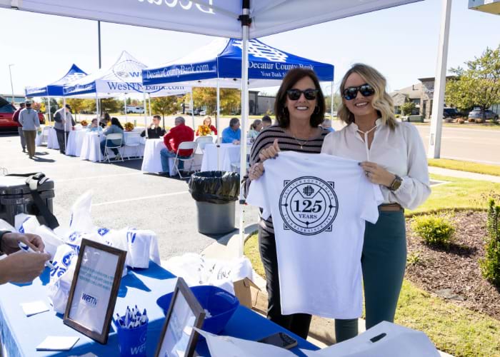 two women in West Tennessee Tent holding up 125th anniversary shirt