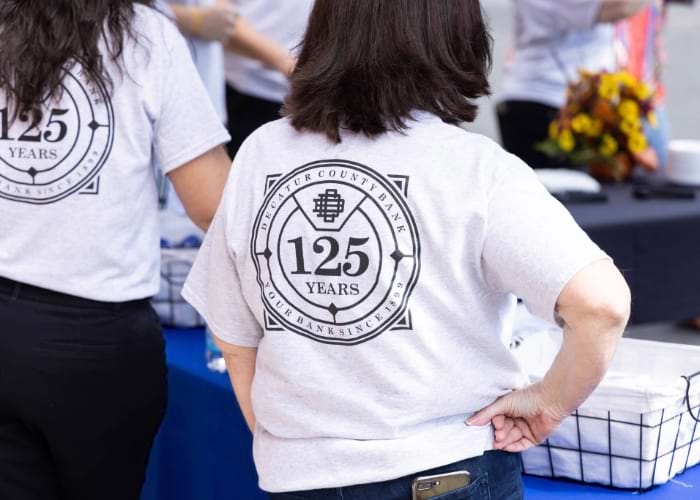 people facing away from the camera wearing the 125th anniversary shirts