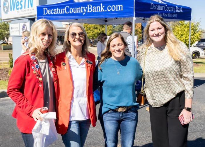 Four women smiling at the camera in front of a Decatur County Bank tent