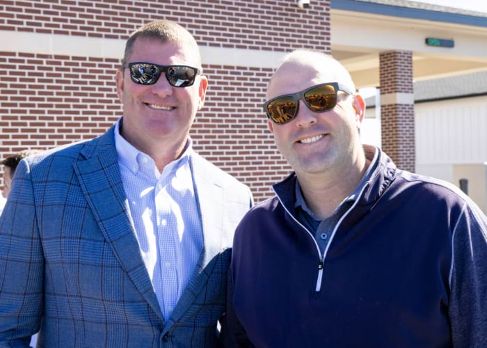 Two men wearing sunglasses smiling at the camera