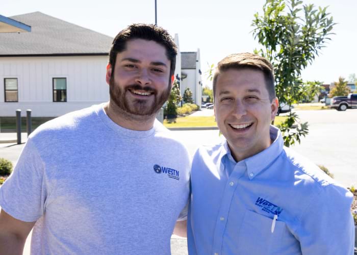 two men wearing West Tennessee Bank shirts smiling at the camera
