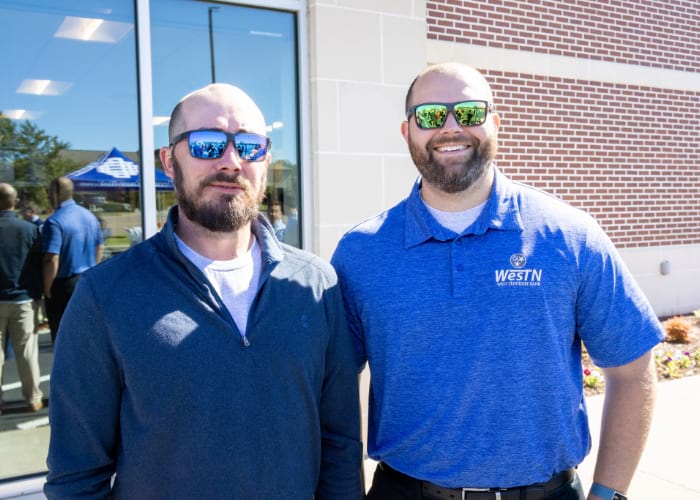 Two men wearing sunglasses smiling at the camera