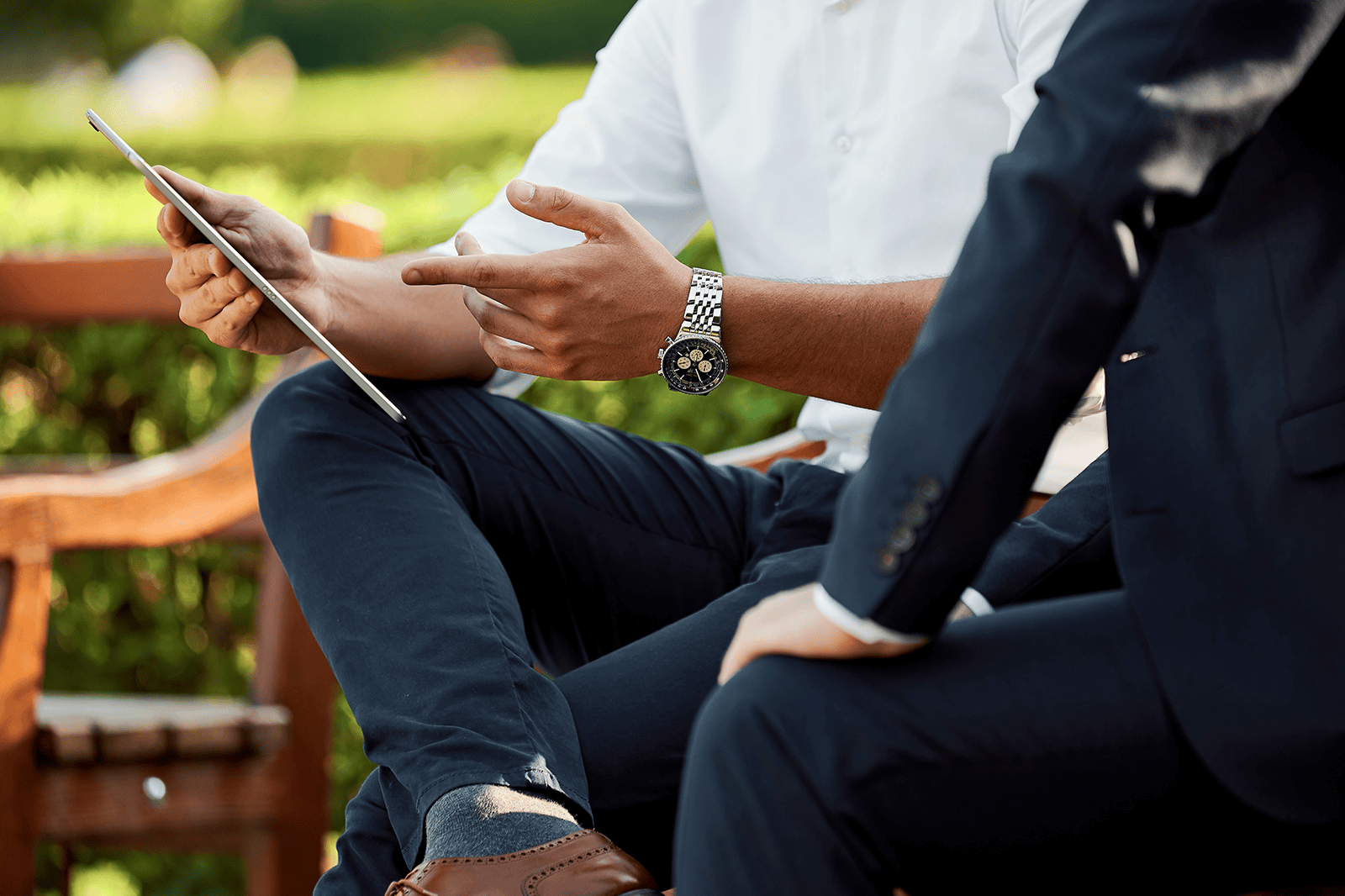 man with watch holding ipad pointing to the screen