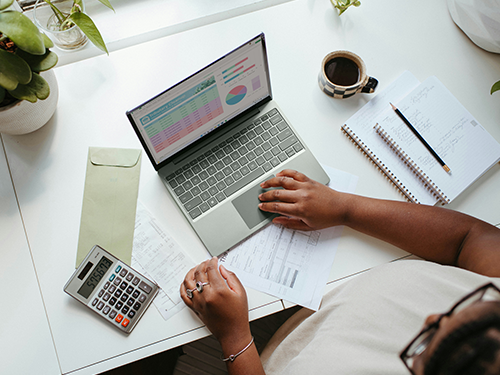 aerial view of woman using calculator and laptop at desk