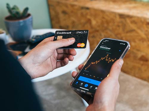 Someone looking at their credit card and their account on their phone