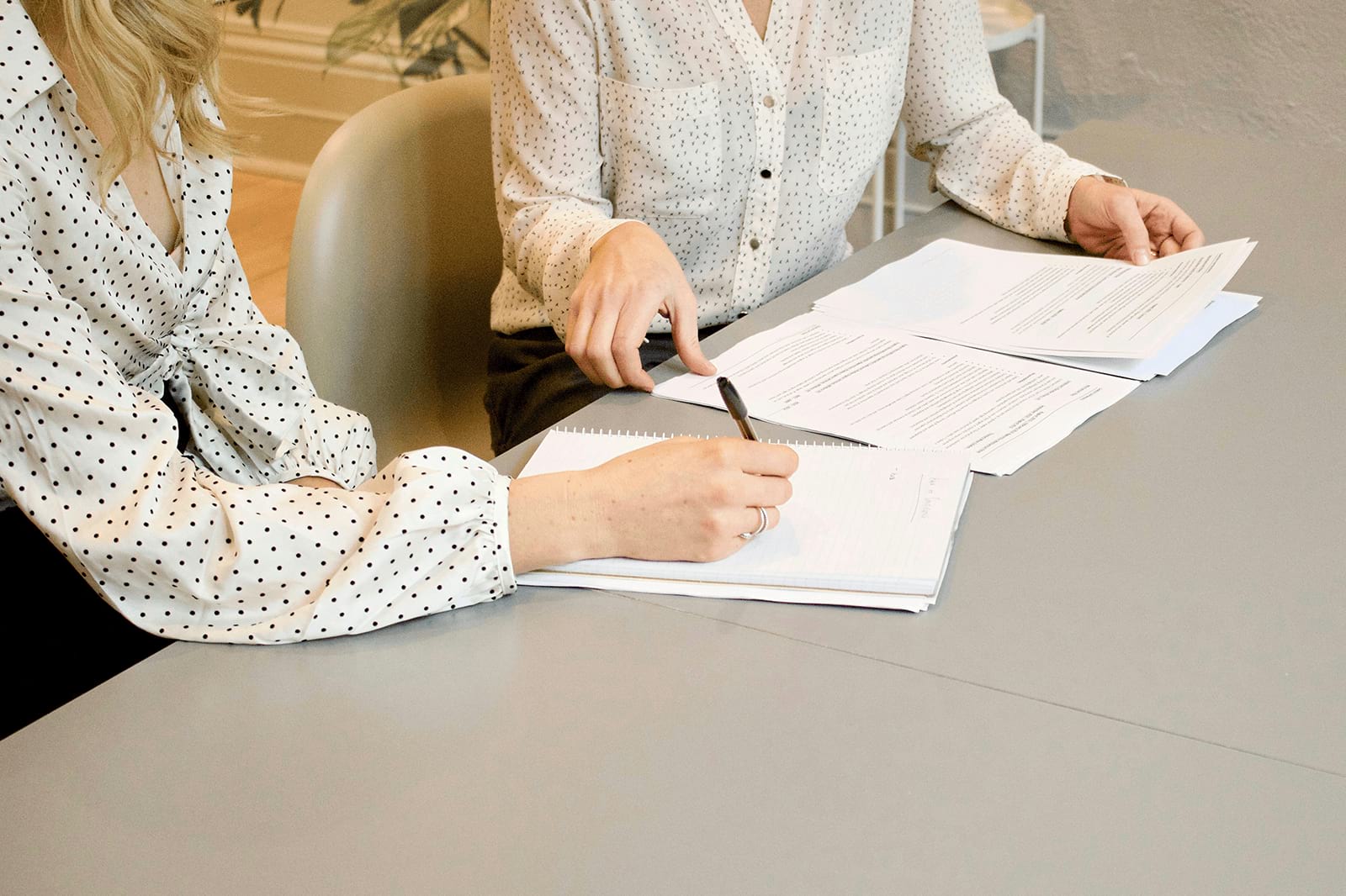 Two women sitting at table reviewing papers
