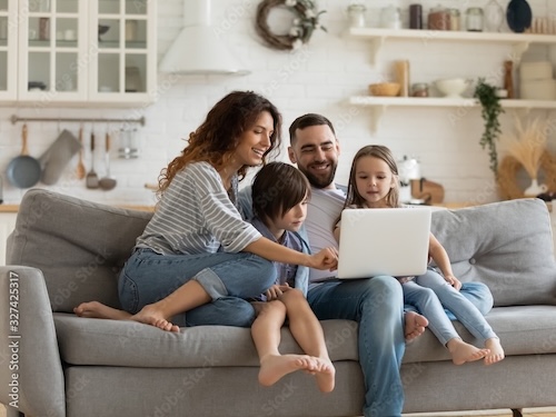 Family sitting together on a couch looking at laptop