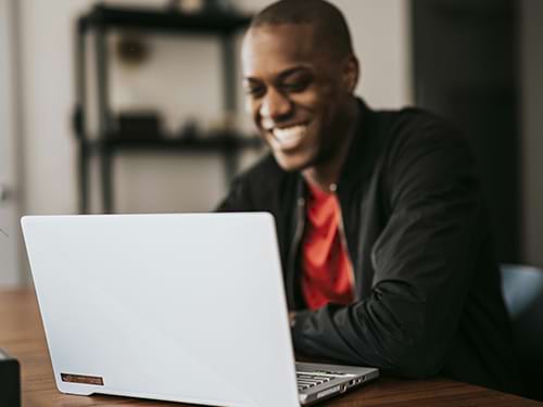 man smiling at laptop while sitting at a table