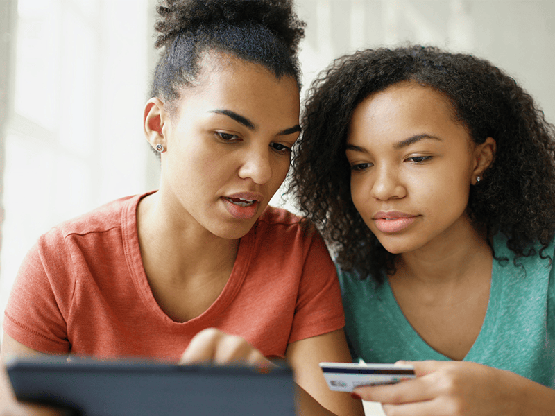 two woman looking at card and device